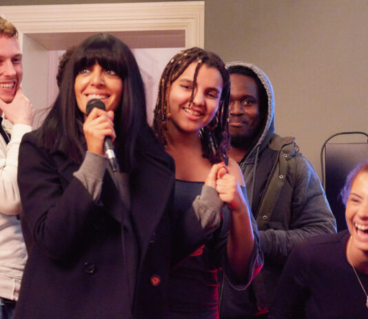 Celebrity Traitors host Claudia Winkleman fronts National Lottery campaign TV host Claudia Winkleman stands with a group of young people holding a microphone in a recording studio.