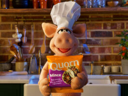 Quorn is back on TV screens A puppet pig wearing a chef hat stands in a kitchen holding a bag of Quorn Mince.