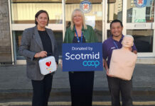 Lynne Ogg, head of membership & community engagement at Scotmid, stands holding a first aid kit next to Moyra Reid, head of marketing, communications and fundraising at St Andrew's First Aid and Daniel Handy. Moyra holds a placard with the Scotmid Co-op logo on it and Daniel holds a dummy used to perform CPR on.