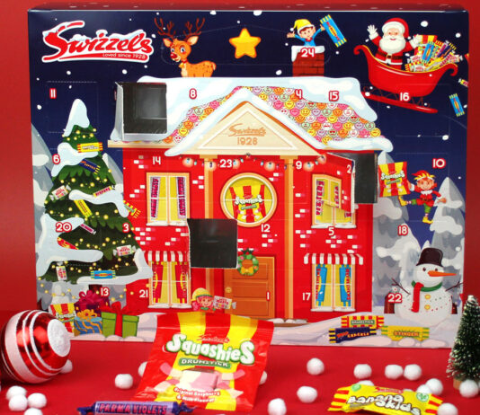 Take a daily trip to the sweet shop with the Swizzels Advent Calendar The Swizzels Advent Calendar for 2025 stands against a red background with packets of Swizzels sweets lying in front of the calendar. Doors one the calendar have also been opened.