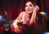 Sophie Ellis Bextor sits at a table holding an Espresso Martini cocktail in a Tia Maria branded glass. There is also a bottle of Tia Maria on the table.