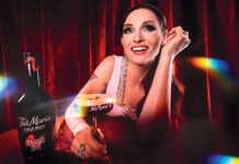 Sophie Ellis Bextor sits at a table holding an Espresso Martini cocktail in a Tia Maria branded glass. There is also a bottle of Tia Maria on the table.