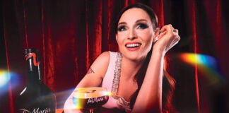 Sophie Ellis Bextor sits at a table holding an Espresso Martini cocktail in a Tia Maria branded glass. There is also a bottle of Tia Maria on the table.