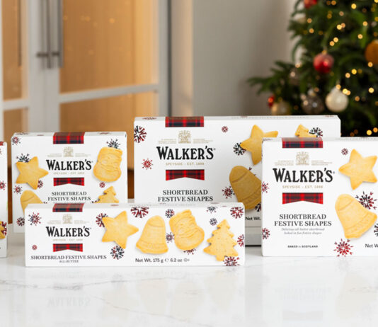 Walker’s Shortbread unveils its Christmas range Packs of Walker's Shortbread 2025 Christmas selection stand upright on a white marble table with a Christmas tree in the background.