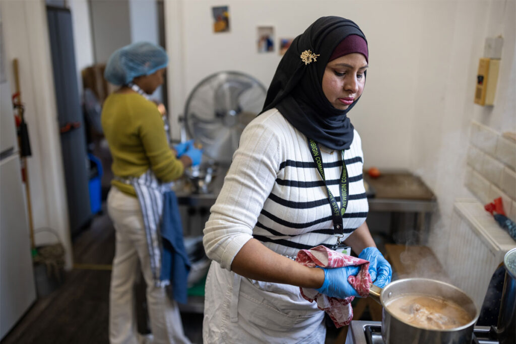 A person stands in a kitchen cooking food in a pot.