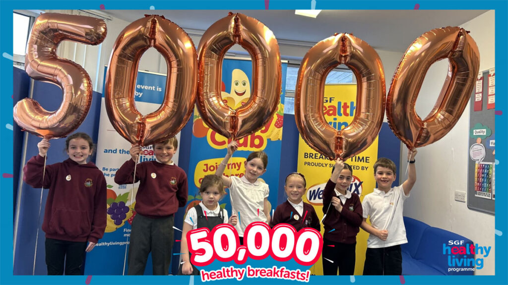 A group of school children hold up balloons that spell out 50,000 to mark 50,000 breakfasts served to kids by the Healthy Living Programme.