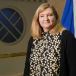 ScotGov publishes HFSS regulations Jenny Minto MSP, minister for public health and women's health, stands in Scottish Parliament with the Scotland flag behind her.