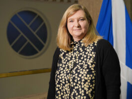 ScotGov publishes HFSS regulations Jenny Minto MSP, minister for public health and women's health, stands in Scottish Parliament with the Scotland flag behind her.
