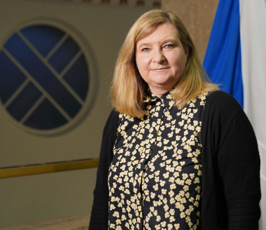 ScotGov publishes HFSS regulations Jenny Minto MSP, minister for public health and women's health, stands in Scottish Parliament with the Scotland flag behind her.