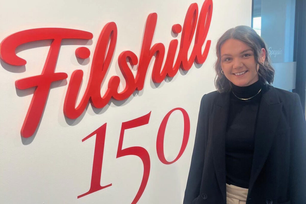 Katie Dempster, marketing manager at Filshill, stands in front of the Filshill 150 logo at the firm's offices.