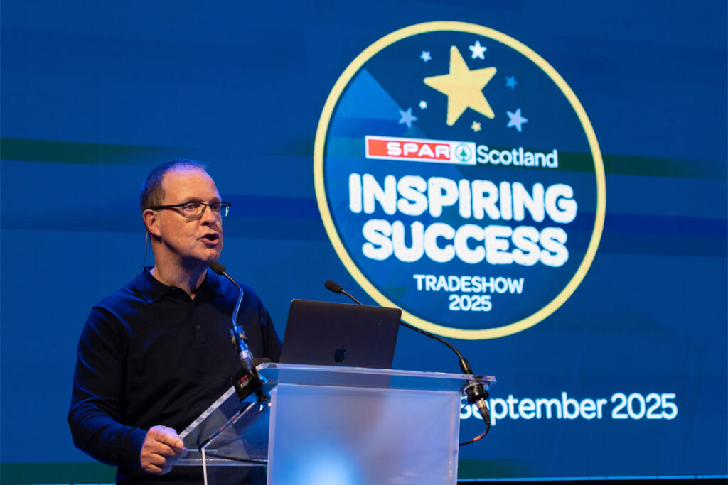 Colin McLean, chief executive at CJ Lang & Son, stands at a podium delivering a talk during the Spar Scotland Tradeshow 2025.