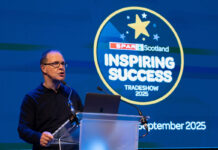 Spar Scotland posts positive results amid turbulent trading period Colin McLean, chief executive at CJ Lang & Son, stands at a podium delivering a talk during the Spar Scotland Tradeshow 2025.