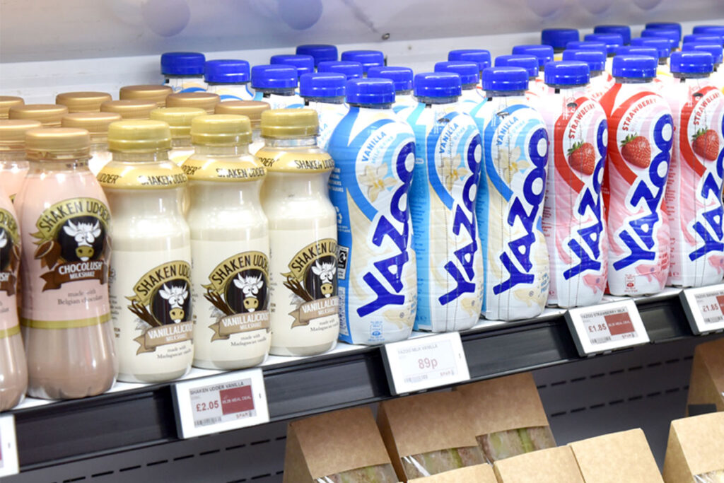 Bottles of milk-based drinks lined up in a chiller shelf.