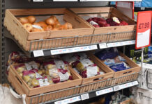 Inflation dips as foods cost rise as Christmas approaches Wooden boxes holding fruit and vegetables sit on top of a store shelf unit.