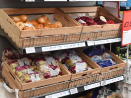Inflation dips as foods cost rise as Christmas approaches Wooden boxes holding fruit and vegetables sit on top of a store shelf unit.