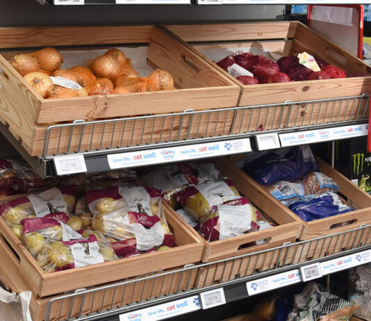 Inflation dips as foods cost rise as Christmas approaches Wooden boxes holding fruit and vegetables sit on top of a store shelf unit.