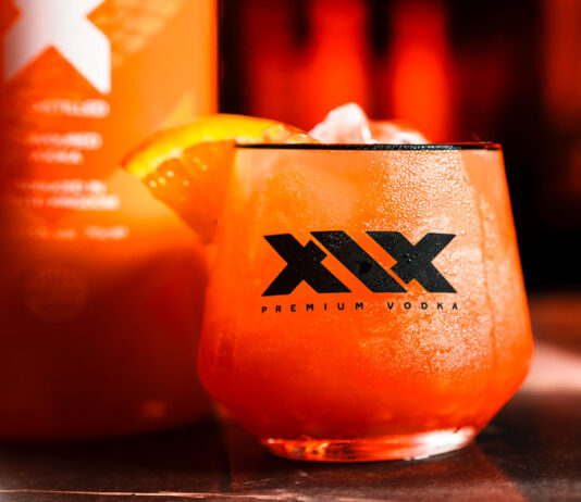 XIX Vodka expands distribution with Red Star Brands partnership A promotional image for the XIX Vodka brand with a cocktail serve in a XIX branded glass with a bottle of the vodka behind the glass.