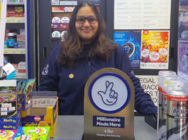 Allwyn shares the win with 20 National Lottery retailers A retailer stands in their store behind the counter with a National Lottery 'Millionaire Made Here' sign on the table.