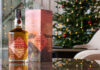 Eden Mill unveils new Art of St Andrews whisky A bottle of Eden Mill Art of St Andrews 2025 single malt stands on a table with its outer packaging next to it with a Christmas tree in the background.