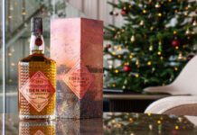 Eden Mill unveils new Art of St Andrews whisky A bottle of Eden Mill Art of St Andrews 2025 single malt stands on a table with its outer packaging next to it with a Christmas tree in the background.