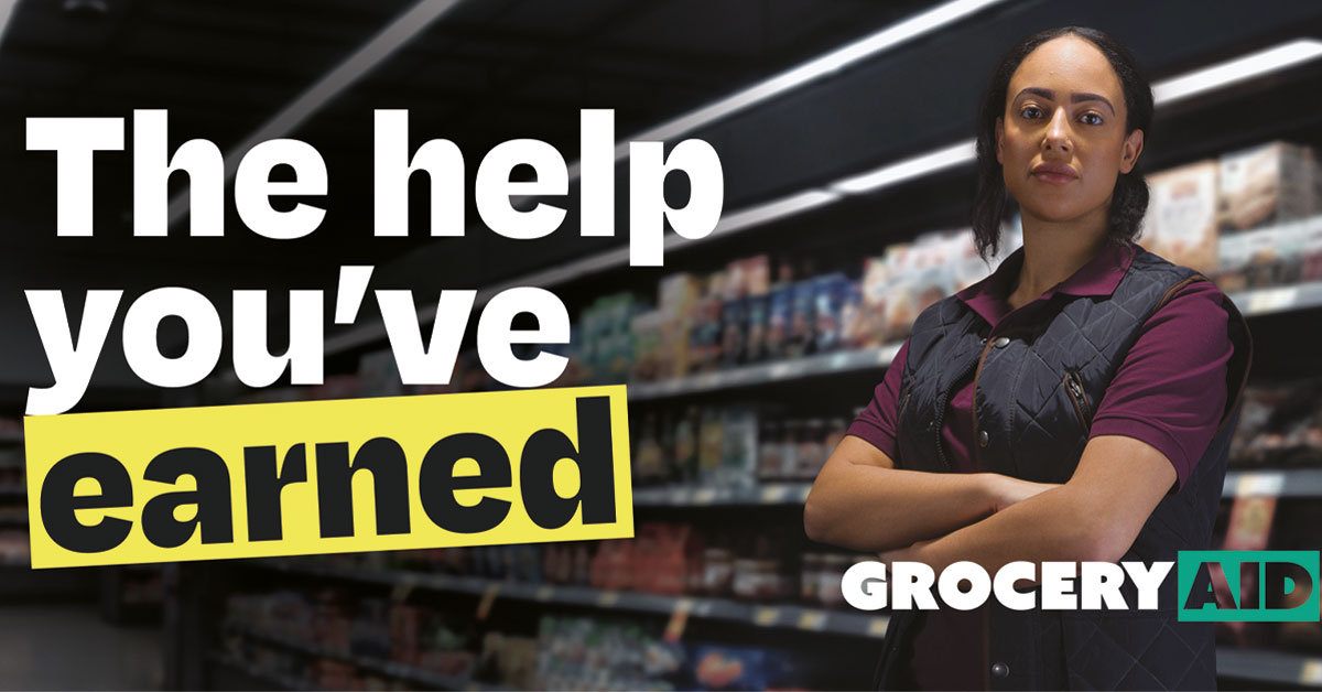 A woman stands with her arms folded in the middle of a shop with the GroceryAid logo in front of her. The text to the left reads "The help you've earned".