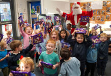 KeyStore spreads festive cheer in local nurseries A group of children celebrate holding Cadbury Christmas Selection boxes with Santa Claus celebrating with them.