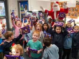 KeyStore spreads festive cheer in local nurseries A group of children celebrate holding Cadbury Christmas Selection boxes with Santa Claus celebrating with them.