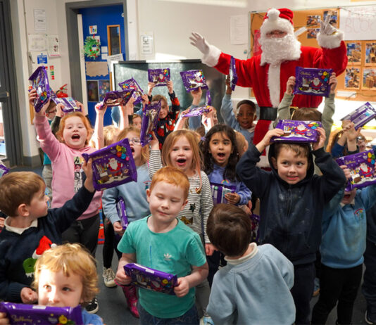 KeyStore spreads festive cheer in local nurseries A group of children celebrate holding Cadbury Christmas Selection boxes with Santa Claus celebrating with them.