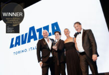 Lavazza named best Commercial Coffee Roaster for third year running A group of people accept the Best European Commercial Coffee Roaster award for Lavazza with the coffee brand's logo on the screen behind the group and the logo for the award in the corner.