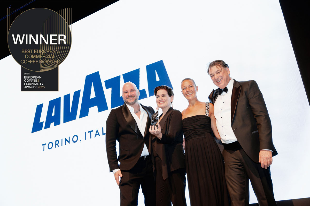 A group of people accept the Best European Commercial Coffee Roaster award for Lavazza with the coffee brand's logo on the screen behind the group and the logo for the award in the corner.