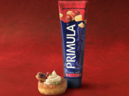 Primula brings back festive Pigs in Blankets flavour A tube of Primula Cheese Pigs in Blankets flavour stands next to a small bite serve using the cheese. This is against a red velvet background.