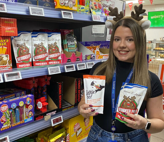 Scotmid scoops up Reindeer Poo treats from Shetland A woman wearing Reindeer antlers holds a pack of Puffin Poo and Reindeer Poo chocolates standing inside a Scotmid store.