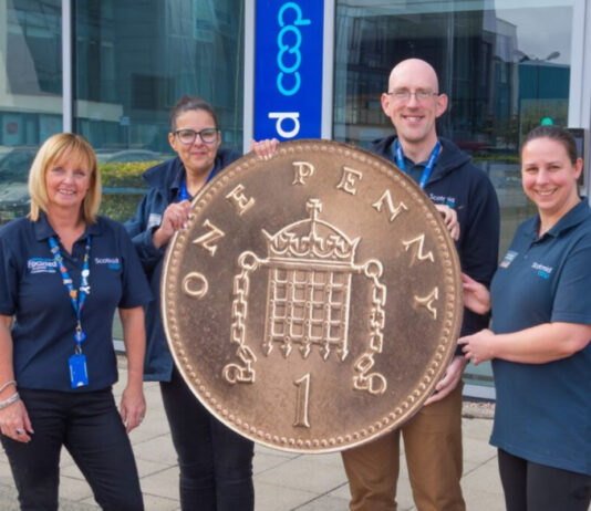 Scotmid rolls out Pennies round up for Alzheimer Scotland support Members of the Scotmid team stand together holding a novelty sized penny coin in front of the firm's headquarters.
