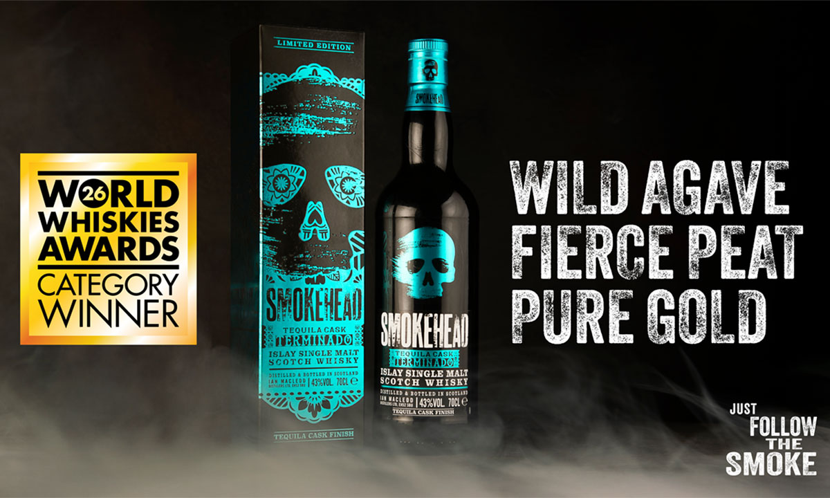 A bottle of Smokehead Terminado and its outer case stand in the middle of a black background with smoke around the bottom of the two. The World Whisky Awards Gold logo is on the left and there is text on the right that reads "WILD AGAVE. FIERCE PEAT. PURE GOLD."