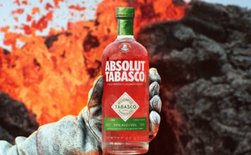 Absolut teams up with Tabasco hot sauce for spicy vodka launch A person holds a bottle of Absolut Tabasco Vodka with an insulated gloved hand against the background of an erupting volcano.