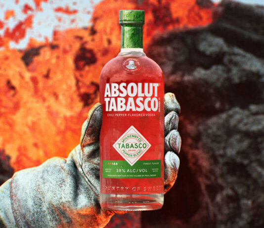 Absolut teams up with Tabasco hot sauce for spicy vodka launch A person holds a bottle of Absolut Tabasco Vodka with an insulated gloved hand against the background of an erupting volcano.