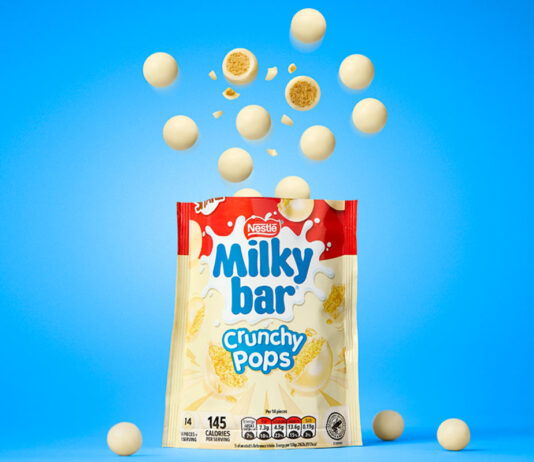Milkybar drops in new Crunchy Pops treat A packet of Milkybar Crunchy Pops stands open against a blue background with pieces of the chocolate rising out of the top of the bag.