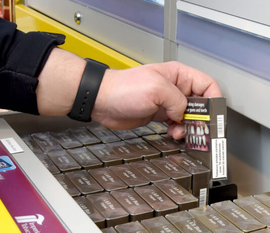 Tobacco & Vapes Bill passes through Parliament A person is lifting out a pack of cigarettes from a drawer at the back of a shop.
