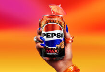Pepsi Max adds in a Tropical flavour A person holds a can of Pepsi Max Tropical against a sunset background. The can has a cocktail umbrella sticking out of the top of it.