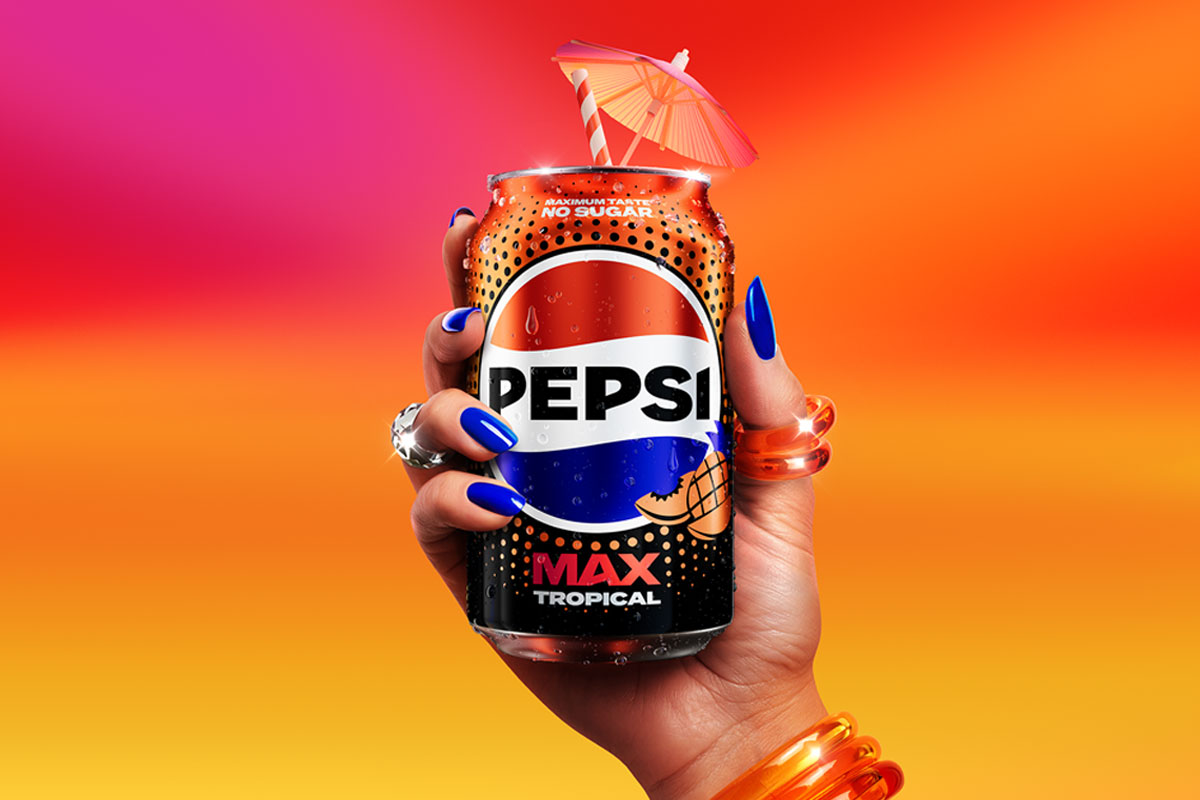 A person holds a can of Pepsi Max Tropical against a sunset background. The can has a cocktail umbrella sticking out of the top of it.