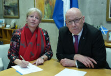 Scottish high streets are ‘one bad budget’ away from closing Shona Robison, finance secretary, and John Swinney, first minister, sit at a desk together with paper on the table and a saltire flag in the background.