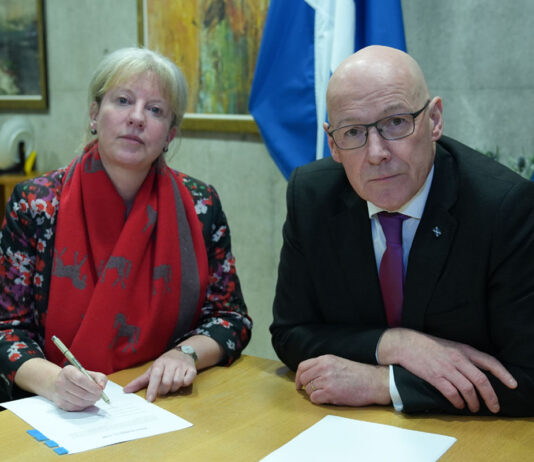 Scottish high streets are ‘one bad budget’ away from closing Shona Robison, finance secretary, and John Swinney, first minister, sit at a desk together with paper on the table and a saltire flag in the background.