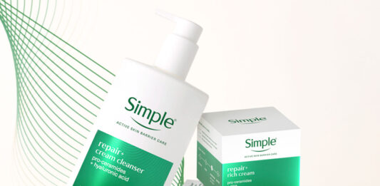 Simple drives premium skincare solution in new range A bottle of Simple Repair+ Cream Cleanser leans on packs of Simple Repair+ Rich Cream and Simple Repair+ Serum against a white background with green design elements.