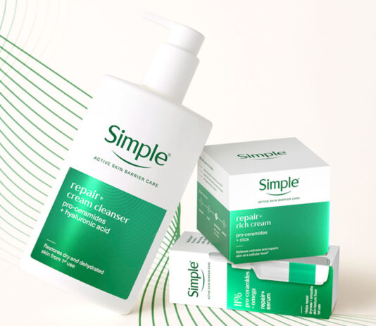 Simple drives premium skincare solution in new range A bottle of Simple Repair+ Cream Cleanser leans on packs of Simple Repair+ Rich Cream and Simple Repair+ Serum against a white background with green design elements.