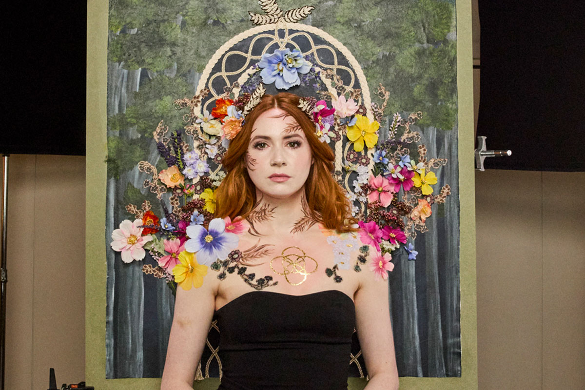 Karen Gillan stands in front of a portrait as part of an art design for Compass Box whisky.