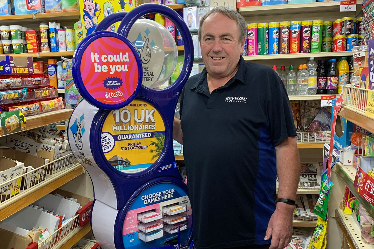 Dennis Forsyth, owner of KeyStore Stranrear, stands next to The National Lottery play station in store.