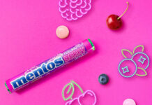 Mentos builds impulse sales with Feeling Berry Good single pack Promotional image of launch for Mentos Feeling Berry Good single pack format launch with pack of the sweets with neon signs of fruit with pieces of fruit against a pink background.