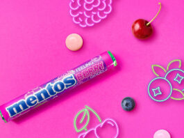 Mentos builds impulse sales with Feeling Berry Good single pack Promotional image of launch for Mentos Feeling Berry Good single pack format launch with pack of the sweets with neon signs of fruit with pieces of fruit against a pink background.