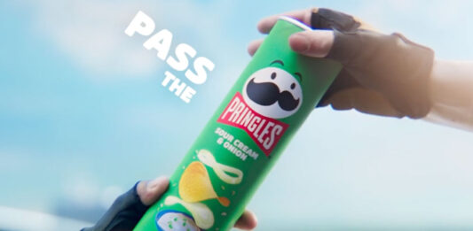 Pringles unveils new marketing platform focused on sharing A person passes a tube of Pringles Sour Cream & Onion to another person.