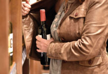 Shoplifting on the rise in Scotland A woman hiding a bottle under her jacket in a store.